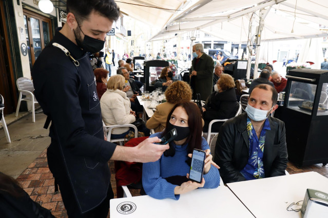 Archivo - Un camarero pide certificado a los clientes en una mesa en la terraza de un bar durante el primer día de petición de Certificados Covid-19 para la hostelería, a 20 de diciembre de 2021 en Málaga (Andalucía, España)
