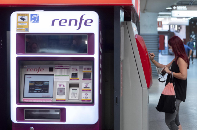 Una mujer compra su billete en las taquillas de venta automática de la estación de tren de Atocha