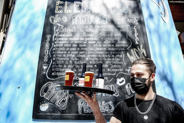 Archivo - Un camarero lleva cervezas artesanales en una terraza, en uno de los bares que participan en ‘Artesana Week Lavapiés’, en la calle Argumosa, a  2 de abril de 2022, en Madrid (España).