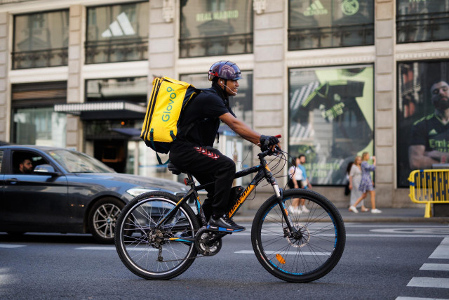 Archivo - Un repartidor de Glovo en bicicleta por una calle del centro de Madrid