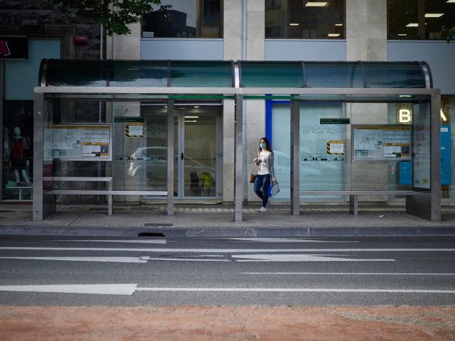 Archivo - Una mujer espera al autobús en Pamplona