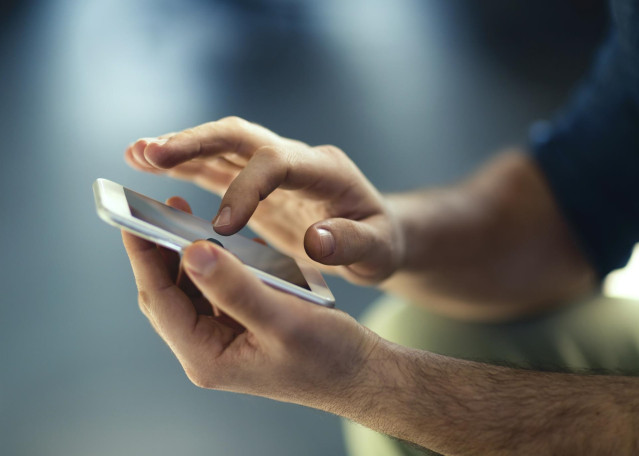 Archivo - Una persona utiliza su teléfono móvil