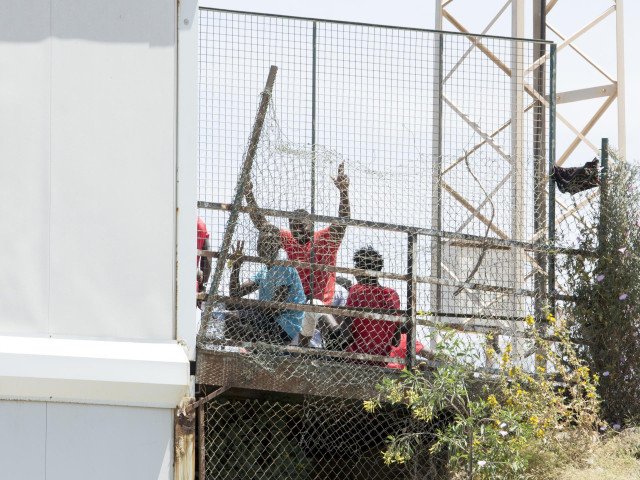 Archivo - Varios migrantes junto a la valla fronteriza de Melilla
