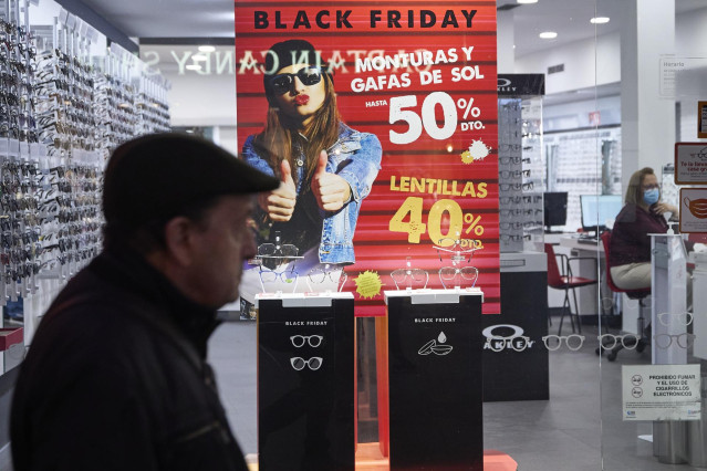 Varias personas pasan por delante de los comercios que anuncian los descuentos del Black Friday,