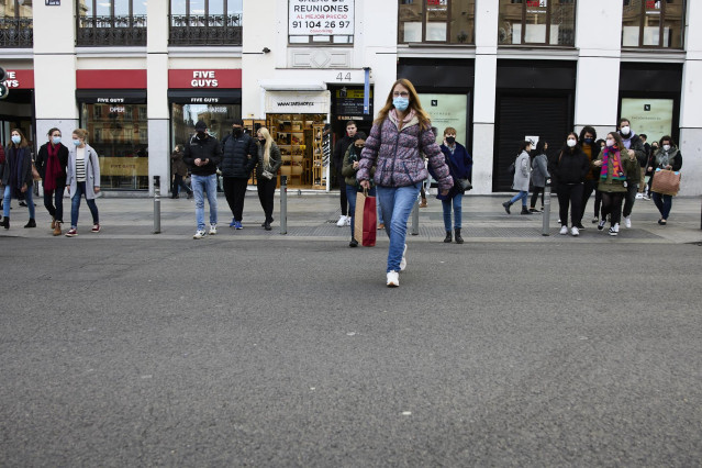 Archivo - Varias personas con bolsas pasean en una calle comercial del centro de Madrid.