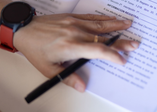 Archivo - Una mujer con un bolígrafo, señala una escritura de compraventa de una hipoteca, a 30 de mayo de 2022, en Madrid (España).