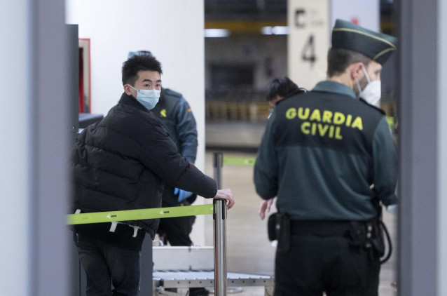 Un agente de Guradia Civil con un pasajero que llega al aeropuerto Adolfo Suárez Madrid-Barajas procedente de un vuelo de Chongqing (China), a 3 de enero de 2023, en Madrid (España).