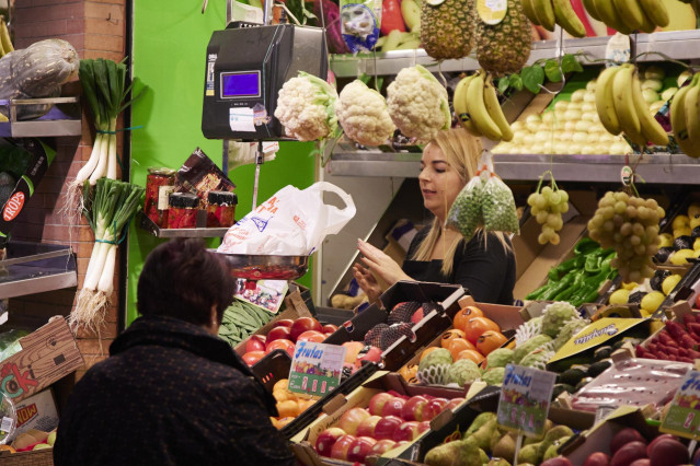 Un dependienta pesa una bolsa con frutas en las compras en los Mercados de Abastos antes de la Navidad , a 23 de diciembre de 2022 en Sevilla (Andalucía, España).