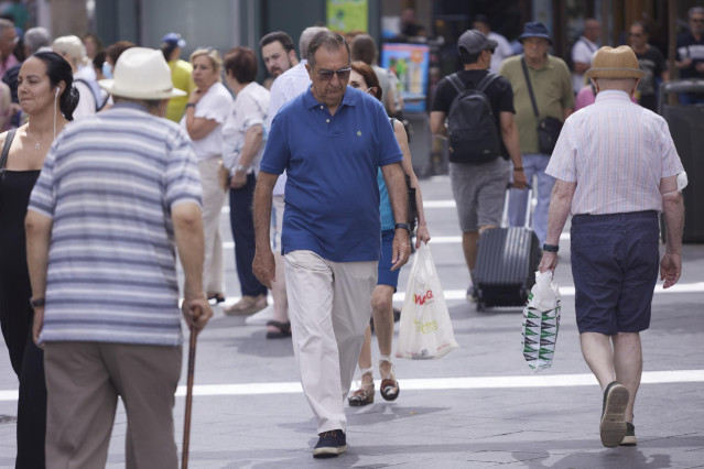 Archivo - Varias personas pasean por una calle de Sevilla.