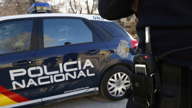 Archivo - Un agente y un coche patrulla de la Policía Nacional