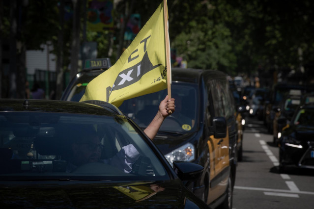 Archivo - Un taxista ondea una bandera en una marcha lenta de taxistas contra los VTC en una imagen de archivo.
