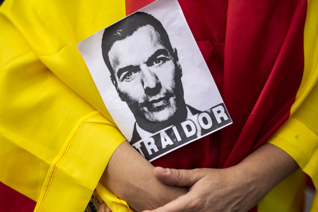 Archivo - Un hombre vestido con la bandera de España sujeta una fotografía de Pedro Sánchez con la palabra 'traidor' durante una manifestación contra el Gobierno, convocada por la plataforma `Pedro Sánchez Dimisión´, a 11 de septiembre de 2021, en Madrid