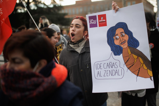 Una mujer con un cartel en el que se lee: 'De cañas al Zendal' durante una concentración en contra de la distinción de la presidenta de la Comunidad de Madrid como Alumna Ilustre de la Complutense