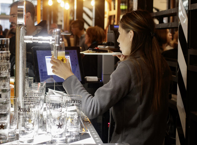 Archivo - Una camarera sirve una cerveza en un bar