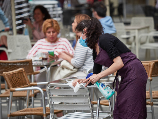 Archivo - Una trabajadora desinfecta las mesas y sillas de una terraza, en una imagen de archivo.