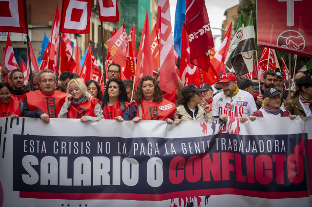 Archivo - Un grupo de personas sostiene banderas y una pancarta durante una movilización convocada por CCOO y UGT desde Puerta de Toledo,
