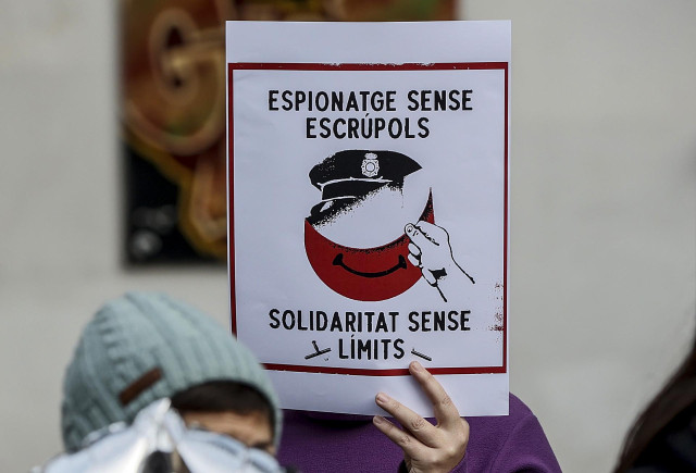 Una mujer sujeta un cartel que hace referencia al espionaje, durante una rueda de prensa de miembros de los movimientos vecinales CSOA l'Horta, Cuidem Benimaclet y Alerta Solidària.