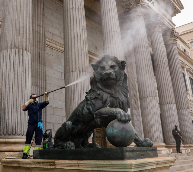 Archivo - Un trabajador limpia uno de los leones del Congreso