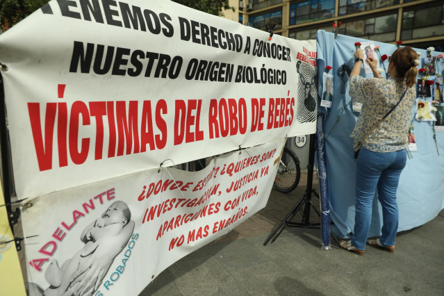 Archivo - Varias personas colocan claveles en un mural colovcado en Madrid con retratos de colaboradores en la búsqueda de víctimas por el robo de bebés en España