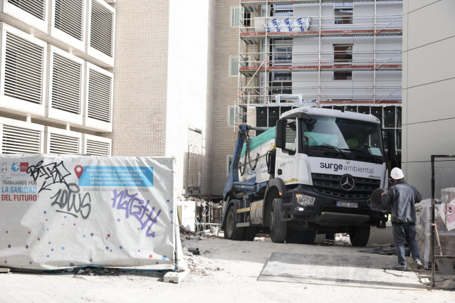 Archivo - Un obrero y un camión contenedor en una obra, a 11 de febrero de 2022, en Madrid