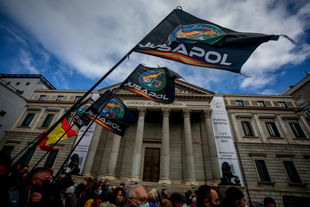 Archivo - Varias personas sostienen banderas de Jusapol en una manifestación contra la reforma de la Ley de Seguridad Ciudadana en noviembre de 2021