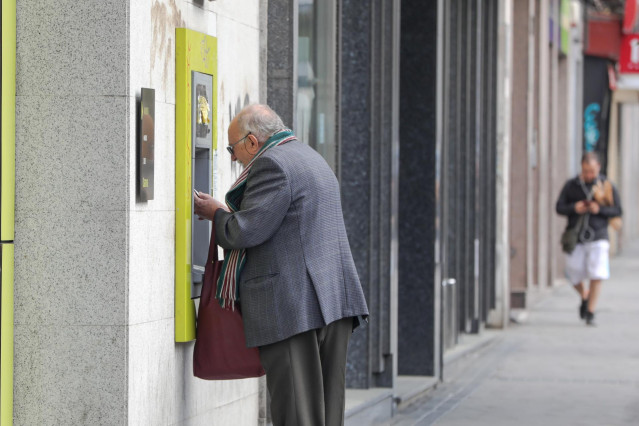 Archivo - Un anciano saca dinero de un cajero de la capital