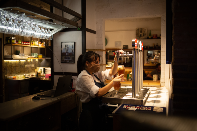 Archivo - Una camarera sirve una cerveza en el interior de un bar en una calle céntrica de Barcelona