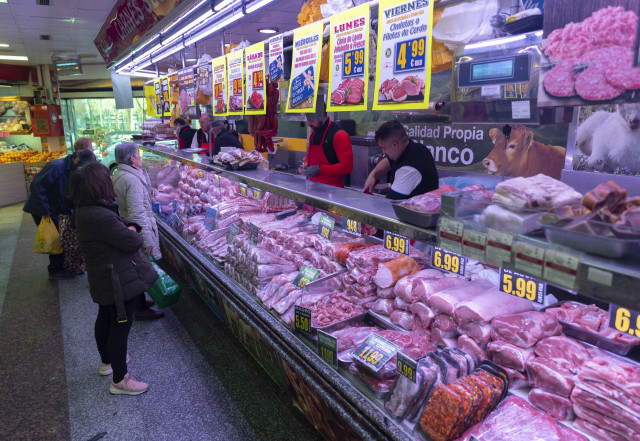 Varias personas compran en una carnicería  en un mercado