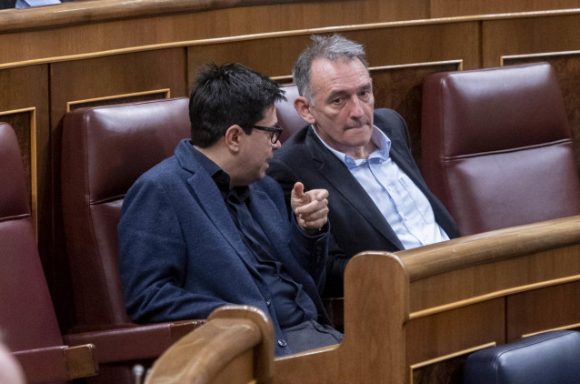 El secretario primero del Congreso y diputado de ECP, Gerardo Pisarello (i), y el secretario general del PCE y diputado de Unidas Podemos en el Congreso, Enrique Santiago (d), conversan  durante una sesión plenaria en el Congreso de los Diputados, a 9 de