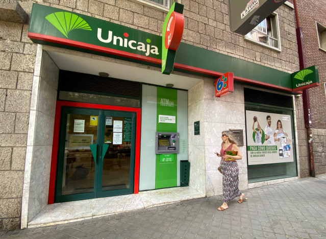 Archivo - Una persona pasa por delante de una oficina de Unicaja, a 18 de julio de 2022, en Madrid (España).