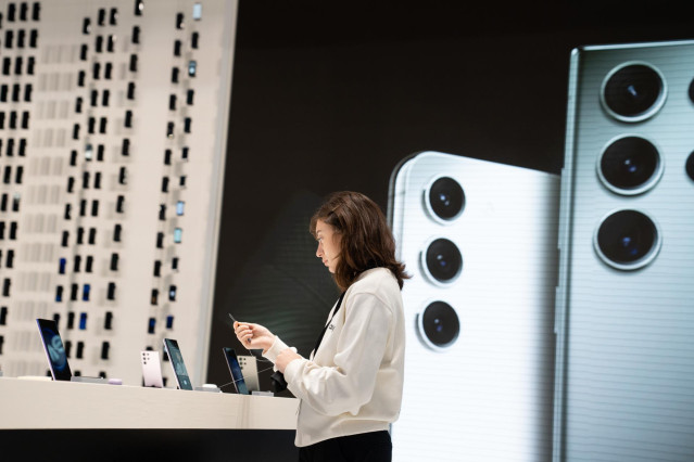 Una mujer frente a un expositor de teléfonos móviles dentro de las inmediaciones de Fira Barcelona, donde se celebra el Mobile World Congress (MWC) 2023, a 1 de marzo de 2023, en L'Hospitalet de Llobregat, Barcelona, Catalunya (España).