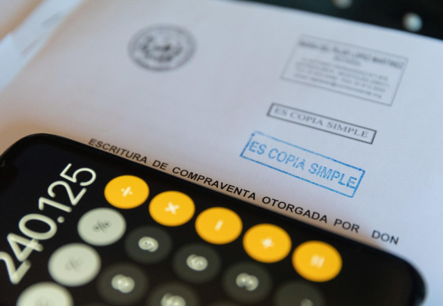 Archivo - Una calculadora y una escritura de compraventa de una hipoteca