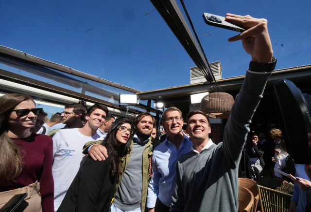 El presidente del PP, Alberto Núñez Feijóo, posa para una foto con jóvenes en un acto de vivienda en Madrid.