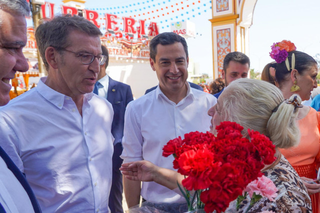 El presidente del PP, Alberto Núñez Feijóo (i), y el presidente del PP-A, Juanma Moreno (d),  con una vendedora de claveles en recinto ferial de Mairena del Alcor para  participan en la presentación de la candidatura del PP la Alcaldía a 20 de abril del 2