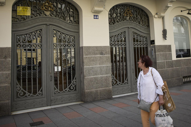 Archivo - Una observa el anuncio de una vivienda de lujo en venta en el barrio de Almagro