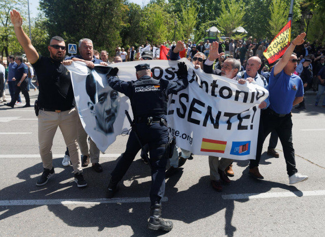 Un agente de Policía Nacional paraliza a varios simpatizantes de la Falange, antes de la llegada del coche fúnebre con los restos de José Antonio Primo de Rivera, en el cementerio sacramental de San Isidro, a 24 de abril de 2023, en Madrid (España).