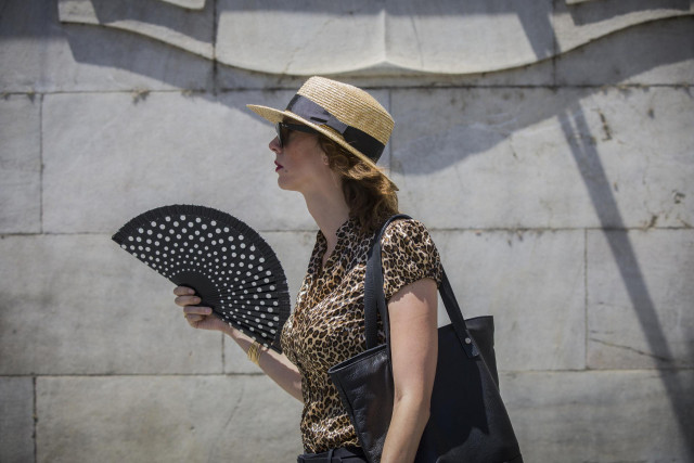 Archivo - Una mujer se abanica mientras camina por la avd. de la Constitución durante la ola de calor africano que ha llegado este jueves a España. En Sevilla (Andalucía, España), a 30 de julio de 2020.