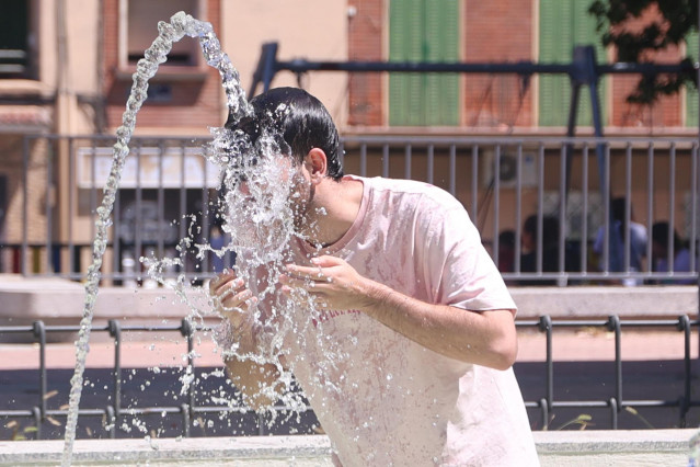 Una persona se refresca en una fuente.