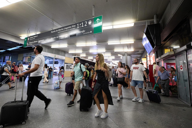 Un grupo de personas con maletas camina por uno de los pasillos de la estaci&oacute;n de Atocha-Almudena Grandes con motivo de la operaci&oacute;n salida de inicios de agosto, en Madrid (Espa&ntilde;a).