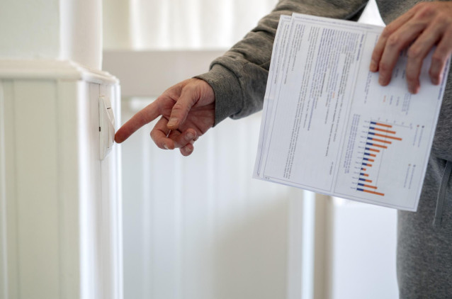 Archivo - Un hombre enciende un interruptor con una factura de luz en la mano, a 3 de enero de 2022, en Madrid, (Espa&ntilde;a).