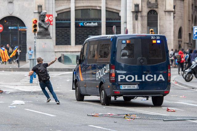 Archivo - Un manifestante independentista al paso de un furgón de la Policía Nacional en la Vía Layetana, en Barcelona