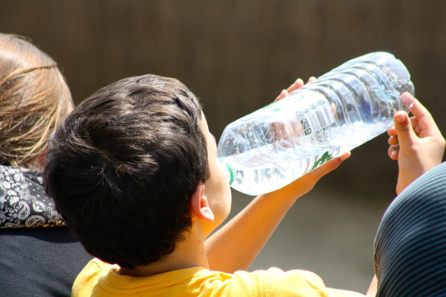 Archivo - Un niño bebe agua en una botella