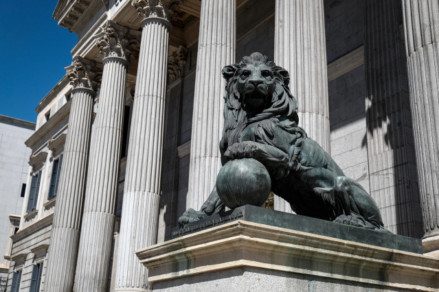 Archivo - Uno de los emblemáticos leones que se encuentran delante de la fachada del Congreso de los Diputados en la Plaza de las Cortes de Madrid.