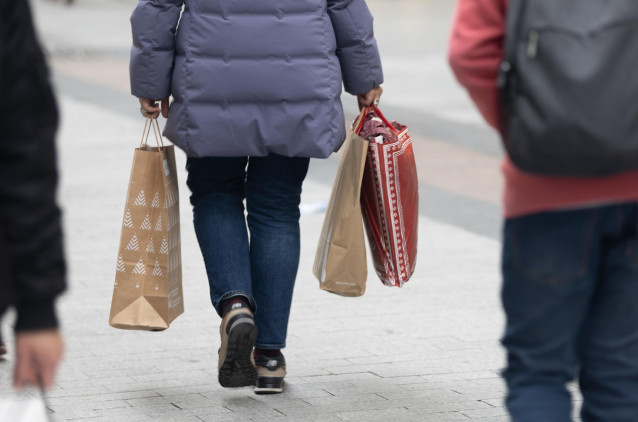 Archivo - Una persona sujeta varias bolsas con compras de Navidad,