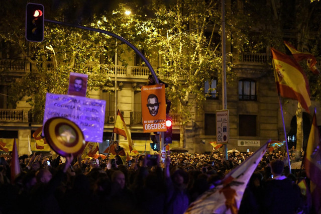Decenas de personas portan banderas, carteles (e incluso un escudo de superhéroe), durante una protesta en la calle Ferraz, a 10 de noviembre de 2023, en Madrid (España).