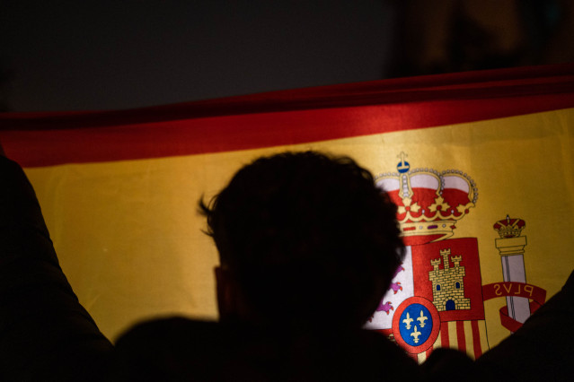 Un manifestante sostiene una bandera española durante la concentración en contra de la amnistía, en la sede del PSOE en la calle Ferraz, a 8 de noviembre de 2023, en Madrid (España).