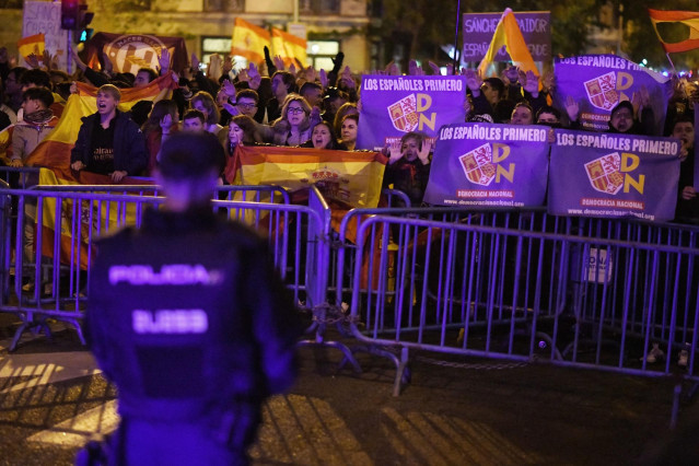 Varias personas muestran banderas de España y carteles de Democracia Nacional, durante una protesta contra la amnistía, frente a la sede del PSOE, a 11 de noviembre de 2023, en Madrid (España).