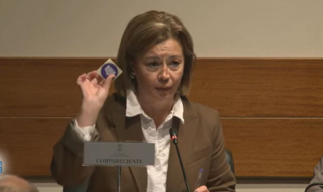 La Fiscal Superior, Esther Fernández,  muestra en la comisión parlamentaria la pegatina identificativa facilitada por el ujier de la Junta a la entrada y que se ha negado a colocar.