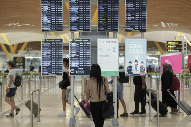 Archivo - Pasajeros cerca de páneles informativos en la terminal T4 del aeropuerto Adolfo Suárez Madrid-Barajas, en Madrid (España).