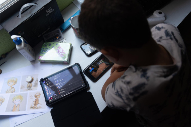Un niño usa el teléfono móvil y una tablet (archivo)